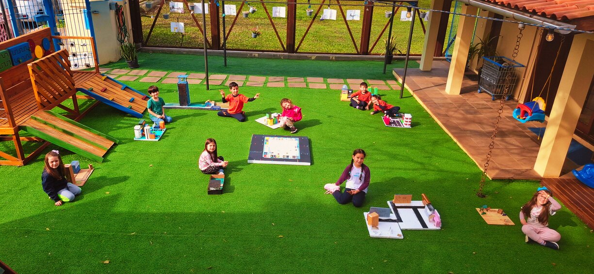 Crianças e educadora brincando juntas no gramado da Mundo Master